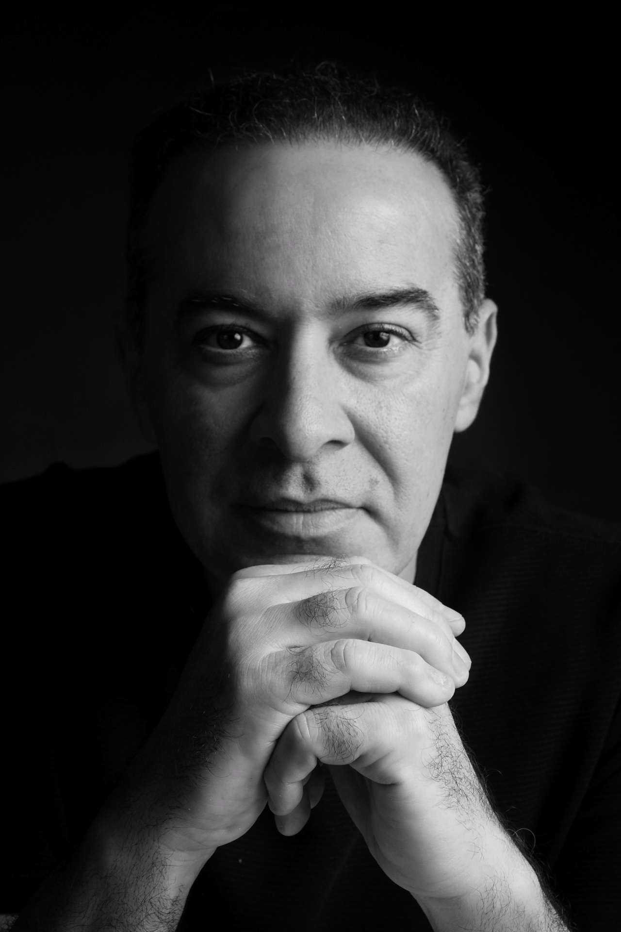 Retrato em preto e branco do Dr. Glauco Almeida, mãos entrelaçadas